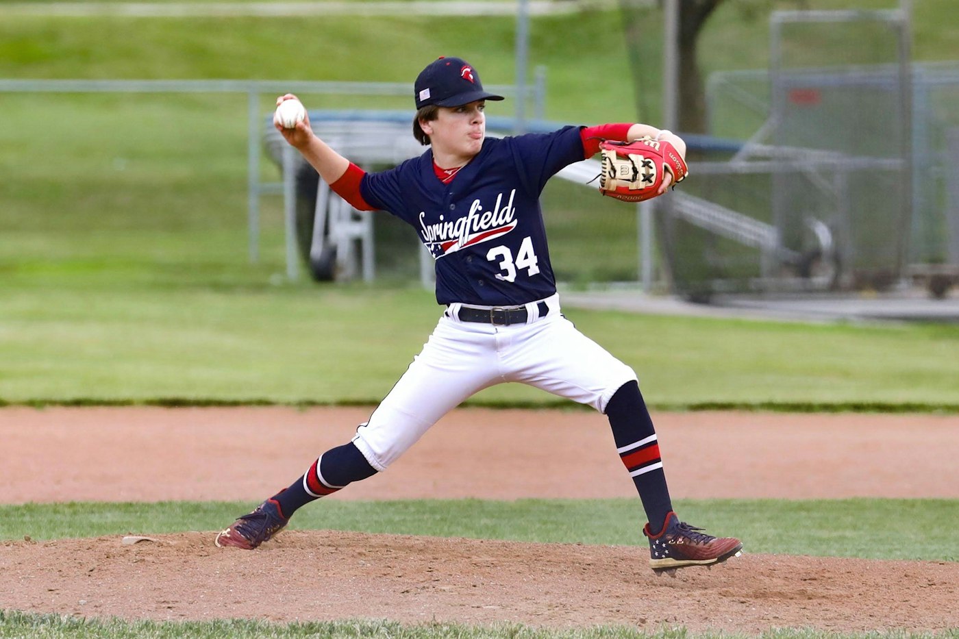 Baseball pitcher in a wide stride, winding up to throw from the mound