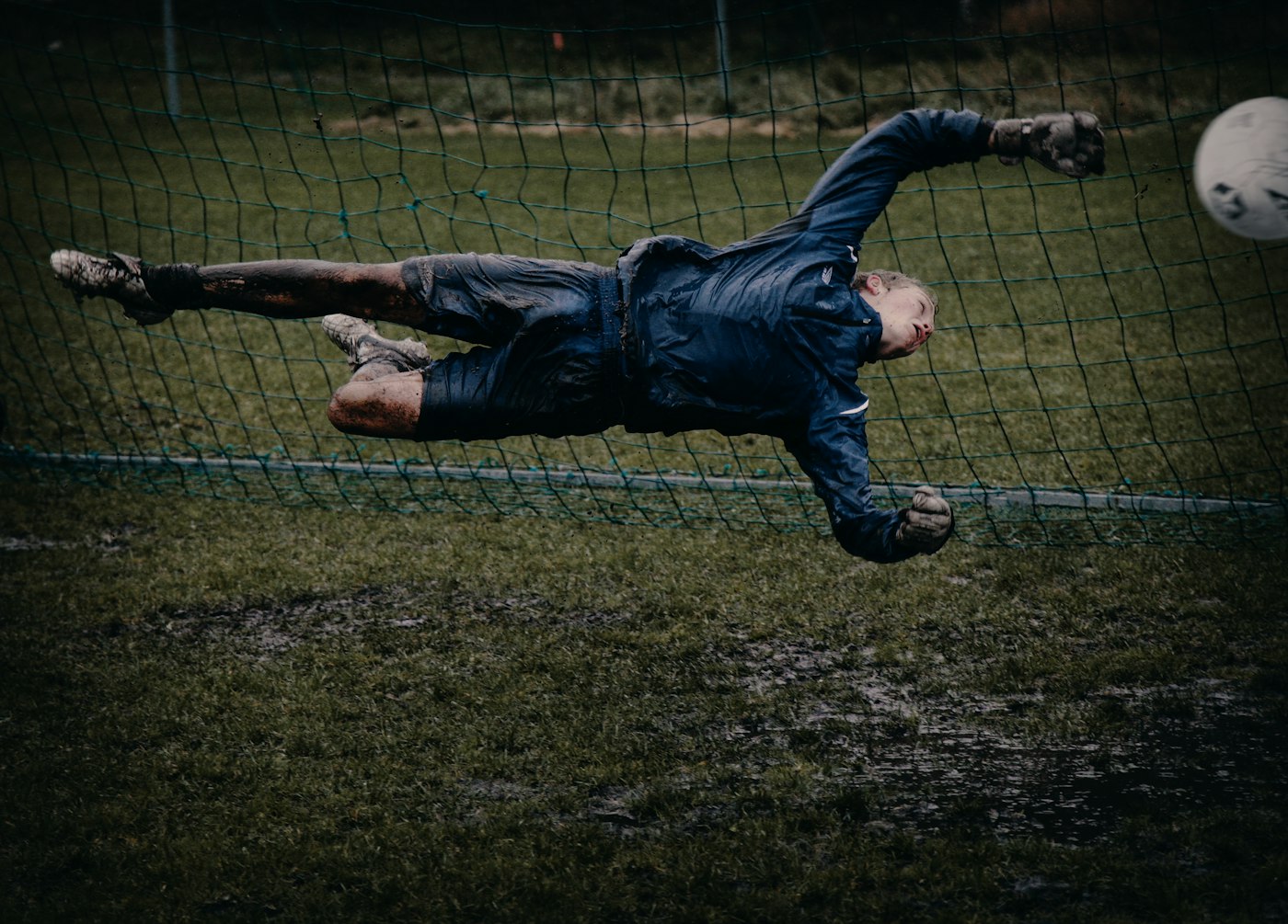 Goalkeeper diving full length through the air to catch a football