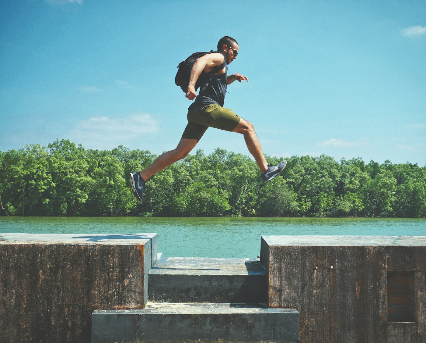 Man leaping between concrete walls by a river, an action pose reference for a mid-air jump
