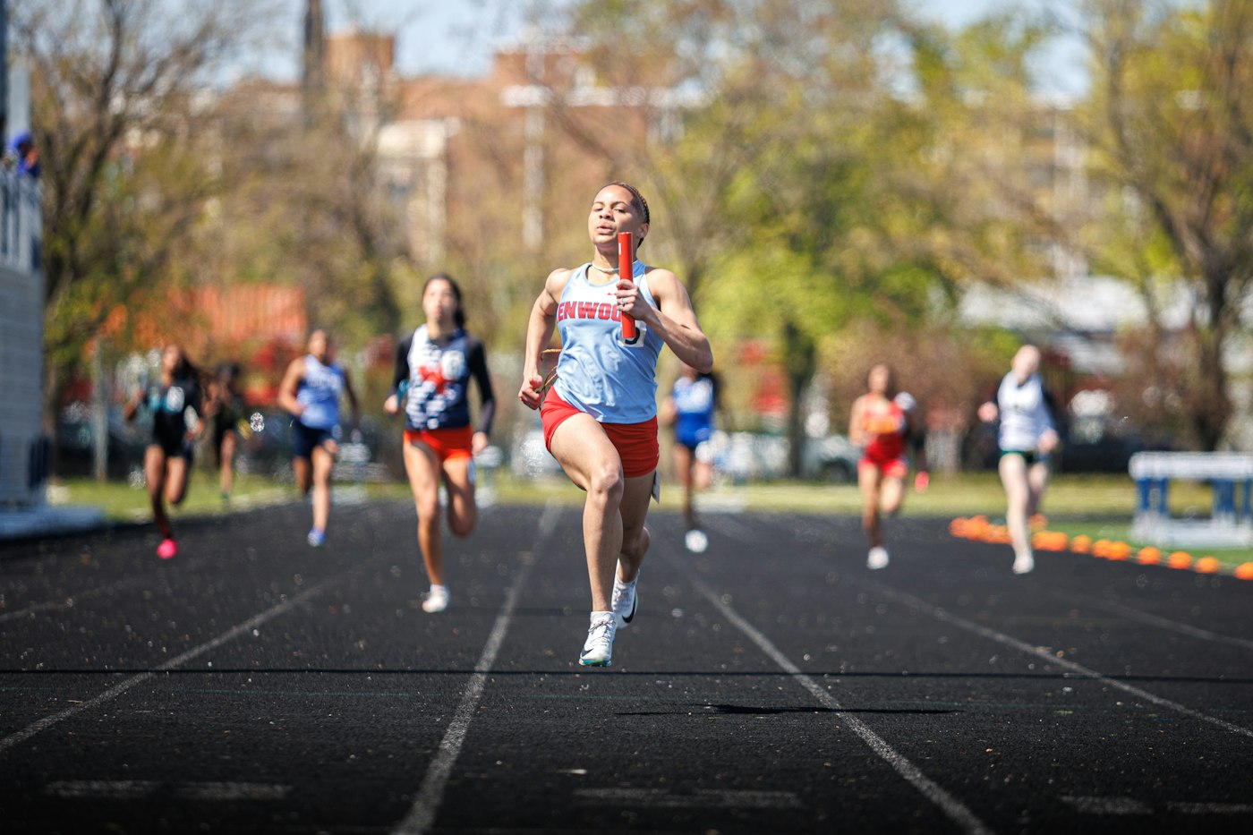 Women sprinters running toward the camera on a track, a front view of the forward lean