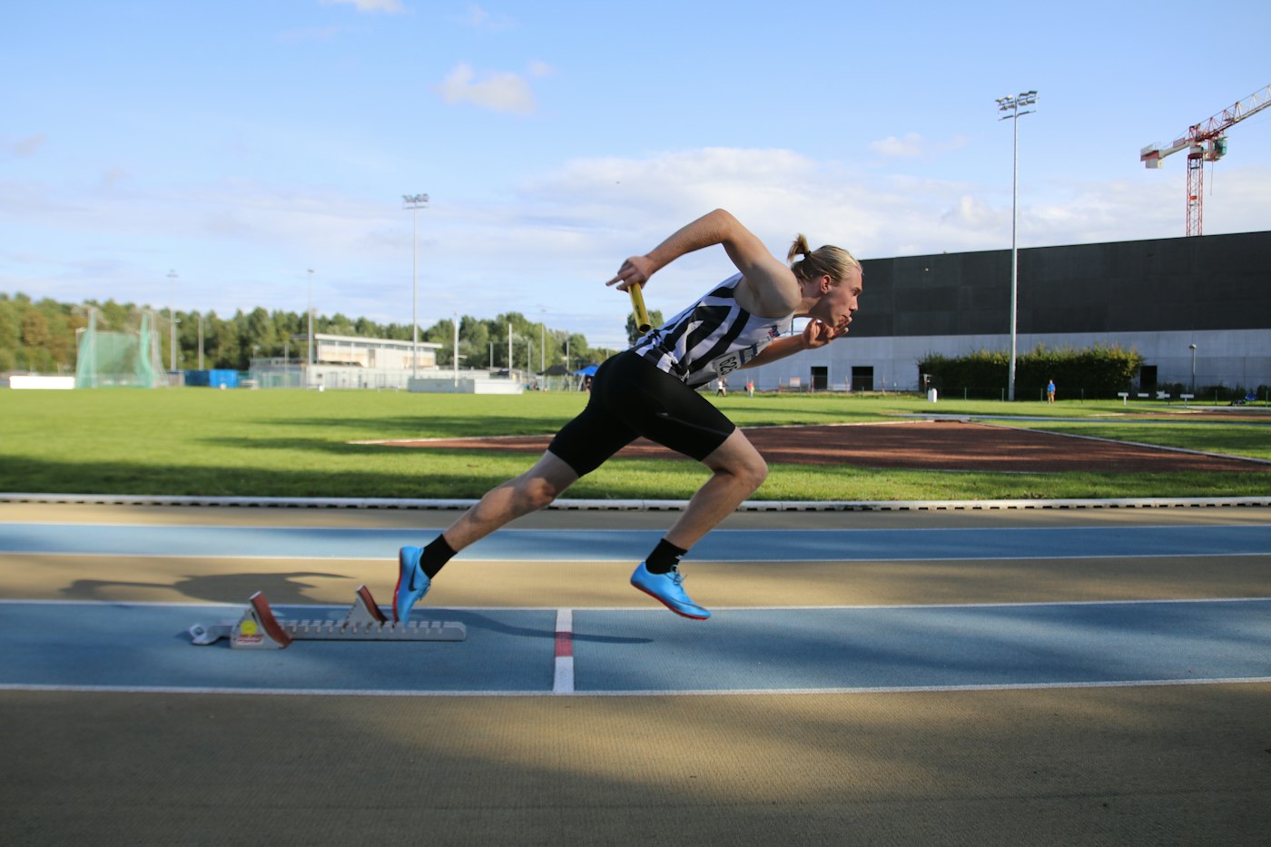 Sprinter driving out of a hard start on an athletics track with a steep forward lean