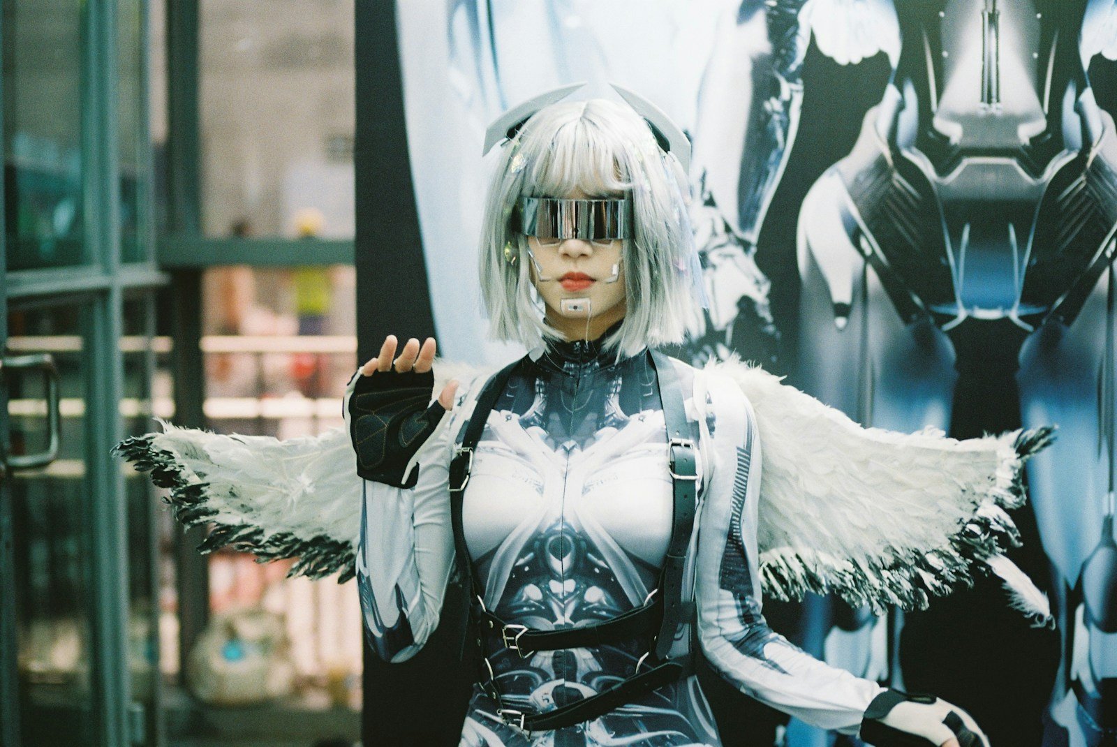 Cosplayer in a futuristic cyborg costume with silver hair, a visor and white wings
