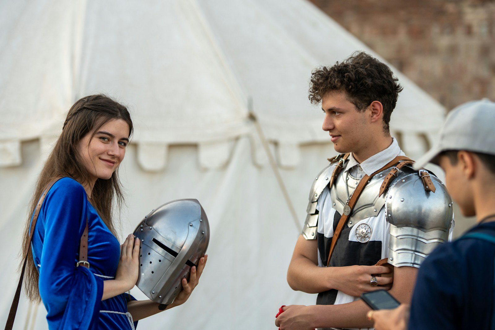 Woman in a blue dress holding a knight's helmet beside a man in armor, a costume reference for drawing