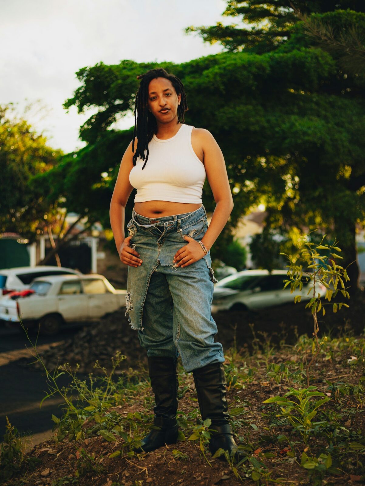 Woman in overalls and a white crop top standing outdoors